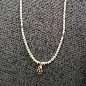 A pearl necklace with a purple diamond